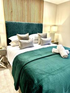 a bedroom with a large bed with a green blanket at Exclusive Marina View Apartment Free Parking in Cardiff