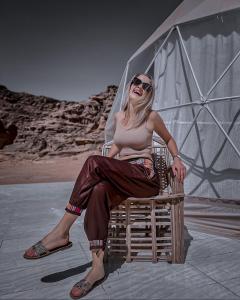 a woman sitting in a chair on the beach at Nasem rum in Wadi Rum