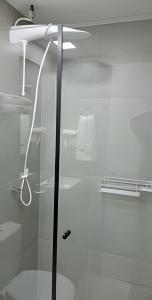 y baño con ducha y puerta de cristal. en Studio Pratico - Centro Poços de Caldas, en Poços de Caldas