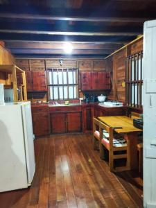 eine Küche mit Holzschränken, einem Tisch und einem Kühlschrank in der Unterkunft Oasis del Bosque 