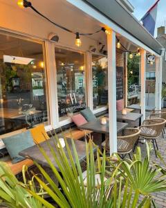 ein Restaurant mit Tischen und Stühlen auf einer Terrasse in der Unterkunft Hotel-Brasserie De Walvisvaarder in Hollum