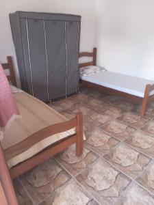 a room with a bed and a cabinet and a tiled floor at Pousada do vovô in Rio das Ostras