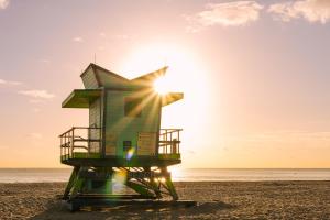 a lifeguard tower on a beach with the sun in the background at Sonder The Abbey in Miami Beach