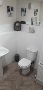 a white bathroom with a toilet and a sink at Spacious Modern Apartment in Glasgow