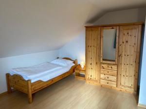 a bedroom with a bed and a large wooden cabinet at Ferienhäuser am Vogelpark - Boddenhaus Tizi in Marlow