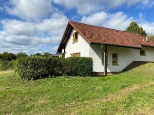 a white house with a red roof on a grass field at Ferienhäuser am Vogelpark - Boddenhaus Tizi in Marlow