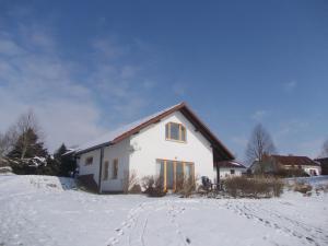 una casa blanca en un campo cubierto de nieve en Ferienhäuser am Vogelpark - Boddenhaus Tizi, en Marlow