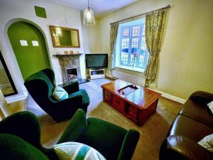 a living room with green furniture and a television at Stratford Centre, Ground Level, Parking nearby in Stratford-upon-Avon