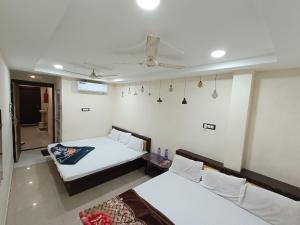 a room with two beds and a ceiling fan at Hotel ST INN in Ujjain