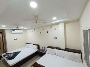 a bedroom with two beds and a ceiling fan at Hotel ST INN in Ujjain