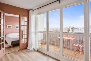 a bedroom with a balcony with a view of a city at Apartment with fantastic views in Pantin - Welkeys in Pantin
