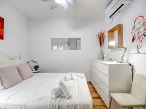een witte slaapkamer met een bed en een stoel bij Espalter White by Hello Homes Sitges in Sitges