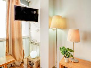een woonkamer met 2 lampen en een tv aan de muur bij Espalter White by Hello Homes Sitges in Sitges +23 foto's