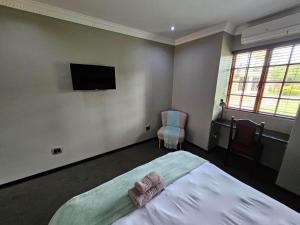 1 dormitorio con 1 cama y TV de pantalla plana en Pietersburg Club, en Polokwane