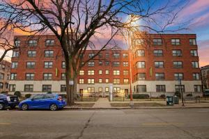 um carro azul estacionado em frente a um grande edifício de tijolos em 1BR Bright and Airy Apt in Hyde Park - Hyde Park 109 and 209 rep em Chicago