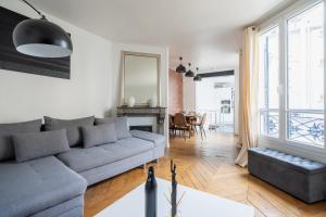 uma sala de estar com um sofá cinzento e uma mesa em Loft spacieux à 10 minutes Champs-Élysées em Levallois-Perret