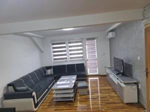 sala de estar con sofá negro y TV en Apartman Danica Foča, en Foča