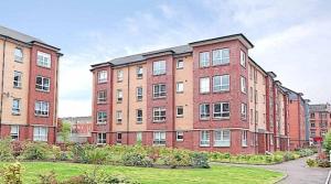 a large brick building with a grass yard in front of it at Spacious Modern Apartment in Glasgow +5 photos