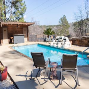 una piscina con 2 sillas frente a una casa en Autumn Woods Lodge, en Evans