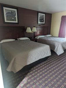 two beds in a hotel room with two lamps at Dollar Inn in Somerset