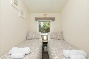 two beds in a small room with a window at Lazy Lodge in Redruth