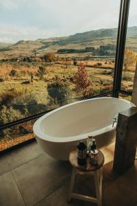 a bath tub in a room with a large window at Sensiri Myst Country House in Dullstroom