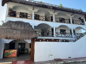a large white building with a thatched roof at Villas ponto in Holbox Island