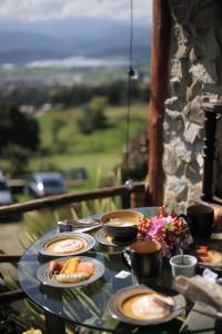 una mesa con platos de comida en el balcón en Cabaña Esmeralda - Seilan Alojamiento Rural en Paipa