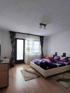 a bedroom with a bed with purple sheets and a window at CASA OANA in Radoşi
