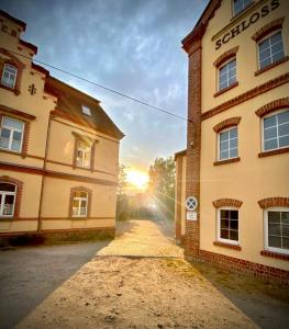 博爾納的住宿－Hotel zur Schlossmühle，两座楼宇之间有太阳落山的空洞小巷