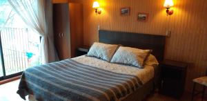 ein Schlafzimmer mit einem Bett mit einer blauen Decke und einem Fenster in der Unterkunft Don Zoilo in Castro