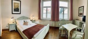 a bedroom with a bed and a table and windows at Hotel zur Schlossmühle in Borna