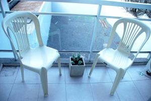 duas cadeiras brancas e um vaso de plantas num alpendre em Departamento en Flores, Ciudad de Buenos Aires em Buenos Aires