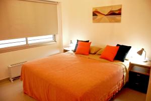 - une chambre avec un grand lit orange et des oreillers orange dans l'établissement Departamento en Flores, Ciudad de Buenos Aires, à Buenos Aires