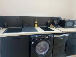 a kitchen with a sink and a washing machine at La balnéothérapie d'Élisa in Dijon