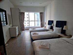 Cette chambre comprend 3 lits et une fenêtre. dans l'établissement Granada Apartments Elite Residence, à Dubaï
