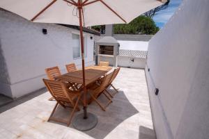 uma mesa e cadeiras de madeira com um guarda-sol num pátio em Playas Art Hotel em Pinamar