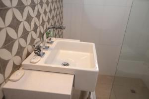 lavabo blanco en un baño con pared en Playas Art Hotel en Pinamar