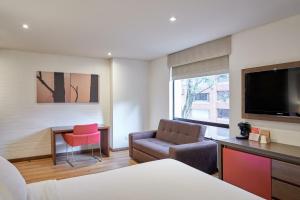 um quarto de hotel com uma cadeira de cama e uma televisão em 84 DC Bogotá em Bogotá