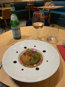 einen Teller mit Essen auf dem Tisch mit einer Flasche Wein in der Unterkunft Kyriad Carcassonne - Aéroport in Carcassonne