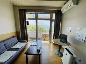 een woonkamer met een bank en een televisie bij Umi no Gohanya Noramare - Vacation STAY 18208v in Masuda