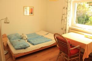 ein kleines Bett in einem Zimmer mit einem Tisch und einem Fenster in der Unterkunft Ferienwohnung kleines Lautertal in Herrlingen