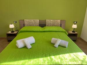Una cama verde con dos almohadas blancas. en VIKY apartments, en Buonfornello