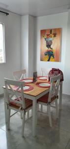 mesa de comedor con 2 sillas y una pintura en Hermoso apartamento iluminado cerca al Metropolita en Barranquilla