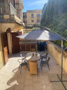 patio ze stołem, krzesłami i parasolem w obiekcie Fort Chambray, Blissful Escape w mieście Għajnsielem