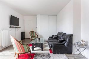 una sala de estar con un sofá de cuero negro y sillas en A proximité de Paris, en Saint-Denis