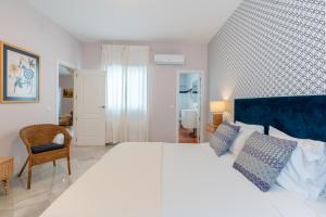 a bedroom with a large white bed with a blue headboard at AtGr Luminoso Ático con Terraza, Calle Antonia Diaz in Seville