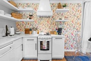 - une cuisine avec des appareils électroménagers blancs et du papier peint à fleurs dans l'établissement Pensacola Whimsy Hideaway: Quirky Apartment Near NAS, à Pensacola