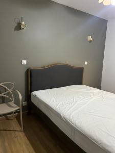 Bett in einem Zimmer mit einem Stuhl und einem weißen Bett in der Unterkunft Belle Vue in Meudon