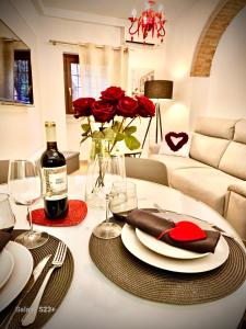 - une table avec des roses rouges et une bouteille de vin dans l'établissement Rosso Verona Apartment, à Vérone